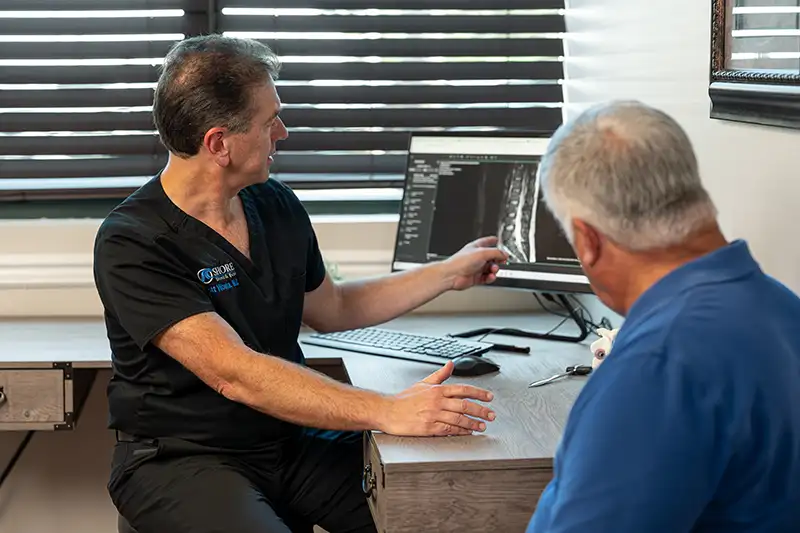 A medical team reviews spinal MRI films, showing how vertebral compression fractures are diagnosed at Shore Spine & Pain.